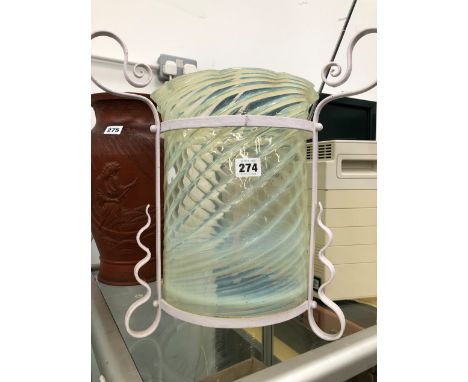 A SPIRAL RIBBED VASELINE GLASS LANTERN IN ARTS AND CRAFTS PAINTED METAL CRADLE