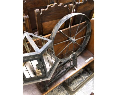 A SMALL IRON WHEEL AND A WROUGHT IRON YARD LANTERN. 