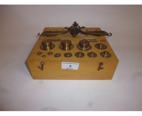 An ornate hanging fish decorated balance scale; and a boxed set of brass weights 