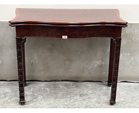 A 19th century mahogany and crossbanded serpentine card table with small drawer to the back panel, raised on blind fret carve