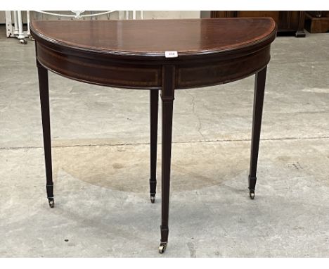 A mahogany and satinwood banded demi-lune card table on square tapered legs with spade terminals and brass castors. 36' wide