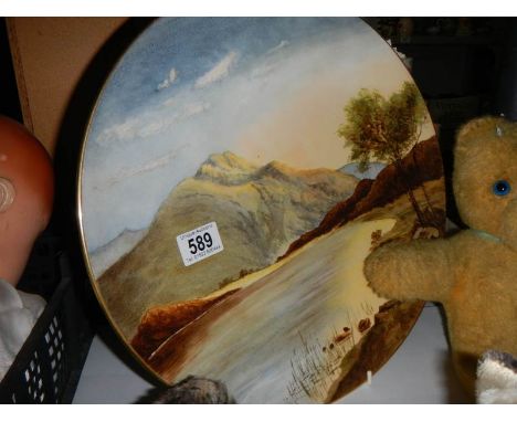 A hand painted wall plaque featuring mountains by Doulton artist M W K Blair, 36 cm diameter. 