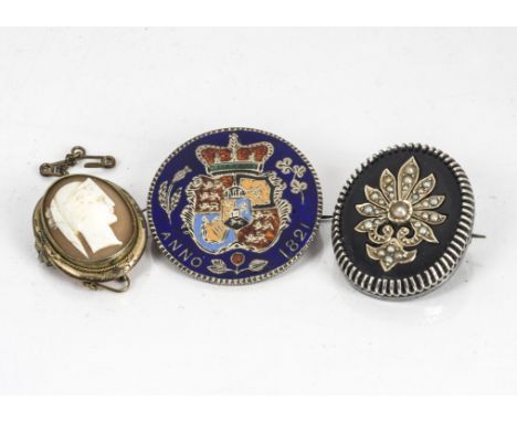 A George IV enamel decorated 1821 half crown, now as a brooch, together with a George VI silver, onyx and seed pearl mourning