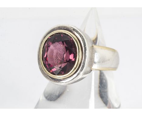 A rubellite silver and 18ct gold dress ring, the oval mixed cut in yellow 18ct gold collet setting surrounded by silver on a 