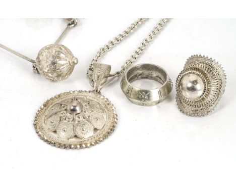 A collection of Ethiopian filigree white metal jewellery, including a roundel medallion, a sphere necklace, a silver ring and
