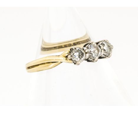 An 18ct gold three stone diamond ring, the three claw set brilliant cuts in white gold claw settings, on twisted shoulders an