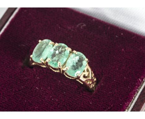 A three stone emerald and 9ct gold dress ring, the oval cuts in claw settings on a pierced gold shank, ring size N, 2.9g, in 