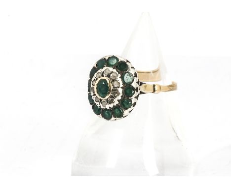 An emerald and diamond continental dress ring, the oval setting with central collet set emeralds surrounded by native cut dia