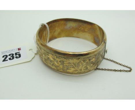 A 9ct Gold Wide Hinged Bangle, allover leaf scroll engraved, hinged to snap clasp (28grams). 