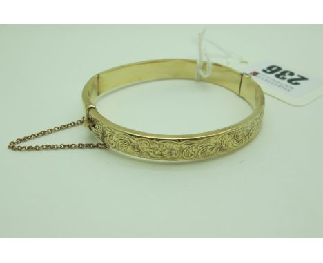 A Chester Hallmarked 9ct Gold Hinged Bangle, leaf scroll engraved to the front, hinged to snap clasp (dents) (9grams).