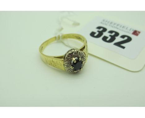 A Sapphire and Diamond Set Oval Cluster Ring, claw and illusion set between textured shoulders, stamped "18C" (finger size R)