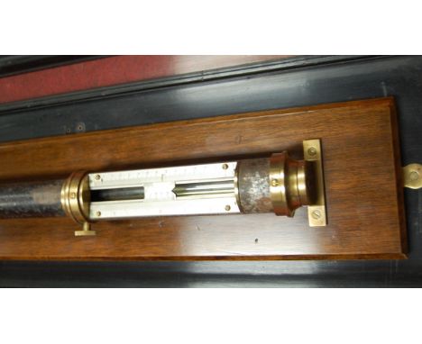 A late 19th century marine stick barometer having an iron case with brass mounts and silvered sliding scale on mahogany plint