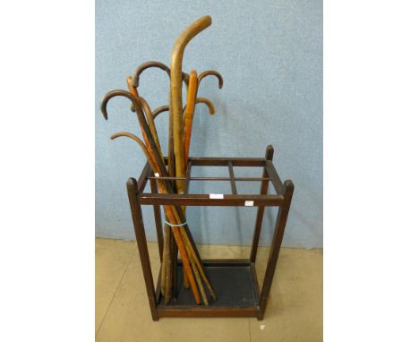 An oak stick stand with walking sticks, three with silver mounts 