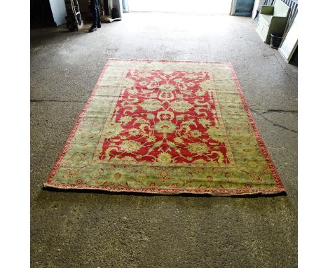 A red and green ground Persian design carpet, 352cm x 268cm (viewing by appointment only as this item is not on display in th