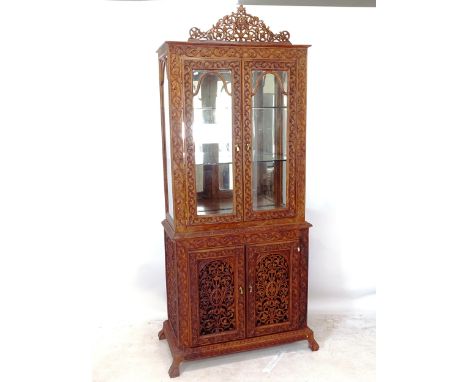 An Oriental design 2-section display cabinet, the top section having 2 glass shelves and 2 glazed panelled doors, the bottom 