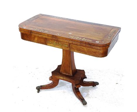 A 19th century rosewood fold over card table, with brass inlay, platform base on sabre legs with brass paw casters, W92cm, H7