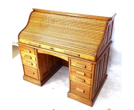 An early 20th century oak tambour-front writing desk, with fitted interior, each pedestal having 4 fitted drawers, the lock e