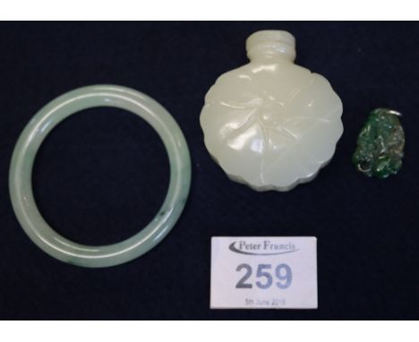 A collection of green hardstone items comprising; a bangle, a carved snuff bottle and a carved and pierced pendant. (B.P. 24%