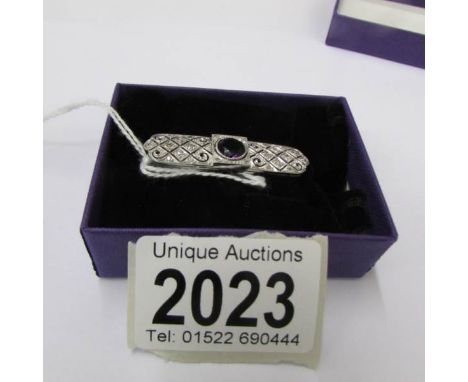 An Art Deco diamond set brooch with central amethyst set in platinum.