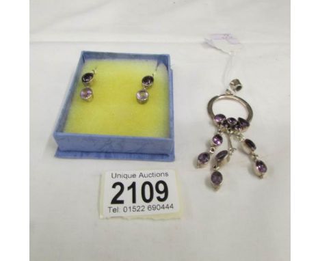 An amethyst drop pendant in silver and a pair of ear pendants in silver set amethyst stone.