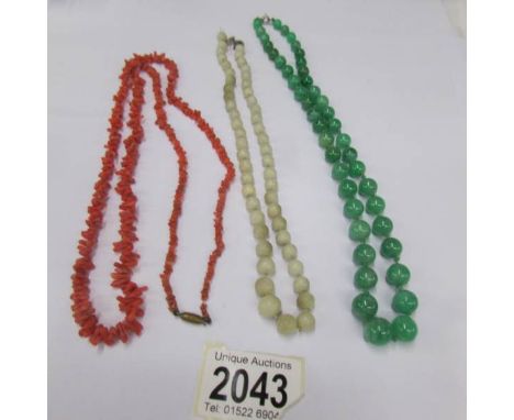 A green jade bead necklace, a white jade bead necklace and a coral necklace.