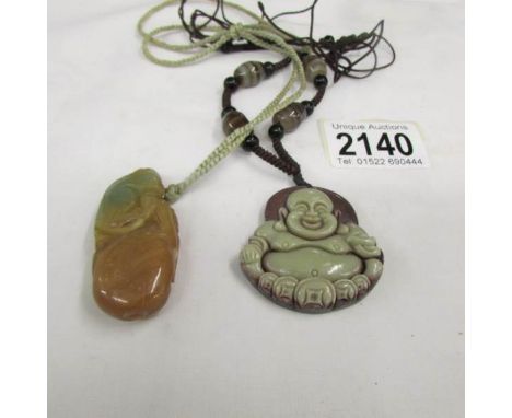 A carved stone Buddha pendant and a jade pendant.