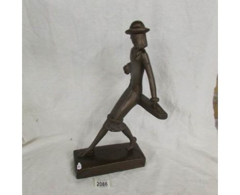 A plaster figure of an art deco lady in a three quarter length coat.