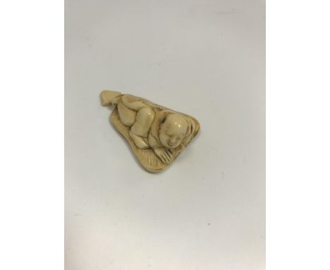 A Japanese Meiji Period carved ivory netsuke as a man upon a palm leaf, inscribed with sun and moon mark to base, 4.6cm L x 2