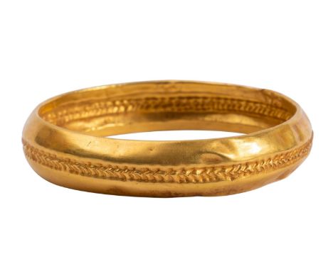 A yellow metal bangle after the Antique,  the folded 'D' shaped  band with stamped herringbone decoration , 34.1g 84mm 