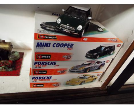 Three Burago 1:18 scale metal model kits comprising Porsche 911, Mini Cooper and a Porsche GT3