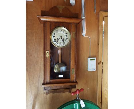 An Arts & Crafts oak cased wall clock with silvered dial and Arabic numerals, inscribed with crossed arrow marks
