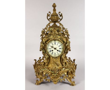 A LATE 19TH CENTURY FRENCH ROCOCO REVIVAL ORMOLU MANTLE CLOCK, with enamel dial, Roman numerals and an urn shape cresting. 2f