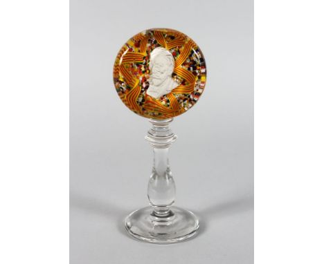 A MILLEFIORI CIRCULAR PEDESTAL PAPERWEIGHT inset with a portrait on a plain turned stem and base. 9ins high.