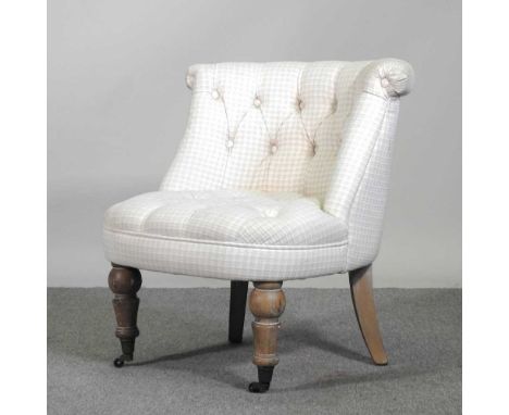 A Victorian style cream upholstered button back tub chair, on turned legs