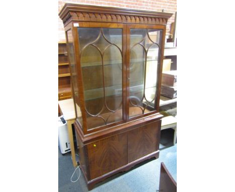 A Georgian style mahogany display cabinet or bookcase, with two glazed doors, cornice over, above two panelled doors raised o