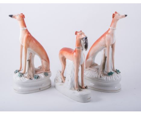 A pair of Staffordshire models of seated greyhounds, shaped bases, 33cm; and another model of a greyhound with a hare, 28cm, 