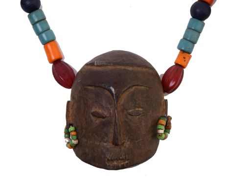 North East India, Naga, a necklace; a carved wooden mask amulet, brass bells and colored tube beads. L. 6,2 cm. (mask) Proven