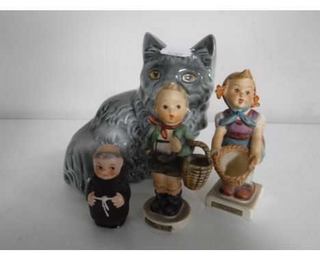 A Goebel money box modelled as a cat together with two Goebel figures - Boy and girl with basket and a miniature monk.