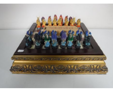 A chess board on gilt base with dragon pieces together with a boxed set of vintage dominoes