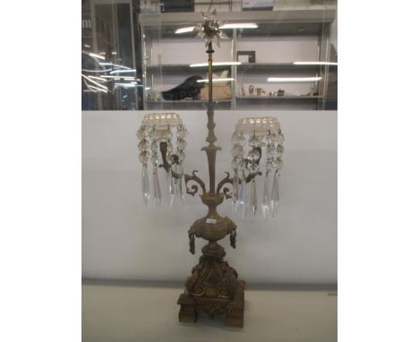 An early 20th century gilt metal two branch candelabrum with crystal drops, star shaped finial and lion ring handles, 67 h, L