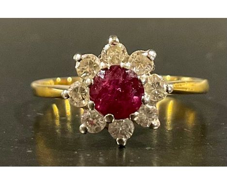 A tested 18ct gold ruby and diamond flower cluster ring, set with an approx. 4.6mm diameter round brilliant cut dark pink rub