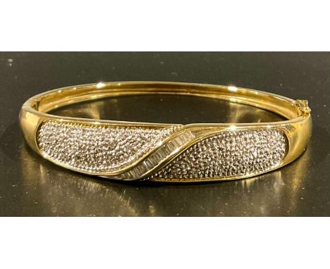 A 9ct yellow and white gold diamond set half hinged bangle, set with with melee tapered baguette cut diamonds and melee round
