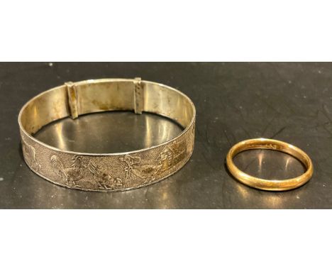 A 9ct gold wedding band, indistinctly dated, 2.7g; an Elizabeth II silver child's bangle, cast with farmyard scenes, Birmingh