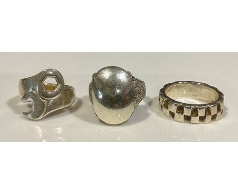 Three silver rings, to include a tested silver poison trinket box ring, size V, a "925" stamped spanner design ring, size O a