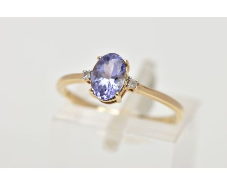 A 9CT GOLD TANZANITE AND DIAMOND RING, designed with a four claw set, oval cut tanzanite, flanked with two small round brilli