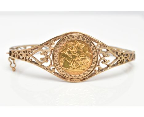 A HALF SOVEREIGN BANGLE, the 1982 half sovereign mounted to the centre of the bangle, to the scrolling openwork hinged bangle
