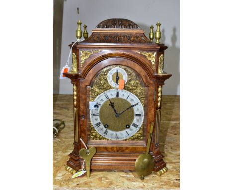 AN EARLY 20TH CENTURY WALNUT AND GILT METAL QUARTER STRIKING BRACKET CLOCK, the carved dome flanked by four brass finials, th