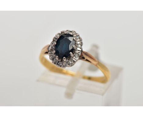 AN 18CT GOLD SAPPHIRE AND DIAMOND CLUSTER RING, designed with an oval cut blue sapphire within a single cut diamond detailed 