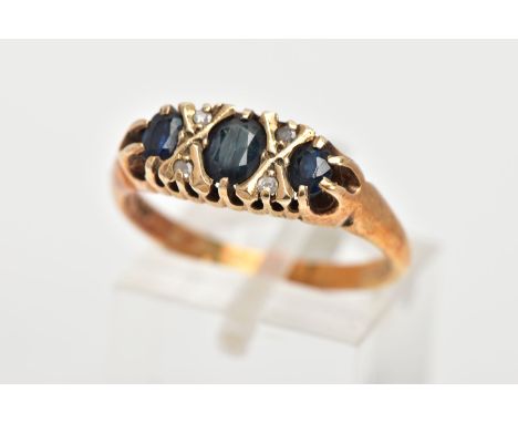 A 9CT GOLD SAPPHIRE AND DIAMOND RING, designed with three graduated oval cut blue sapphires, interspaced with four single cut