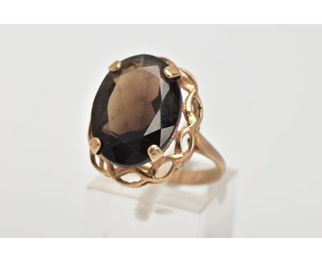 A 9CT GOLD LARGE SMOKEY QUARTZ DRESS RING, centring on a four claw set, oval cut Smokey quartz approximately 17.6mm x 12.8mm,